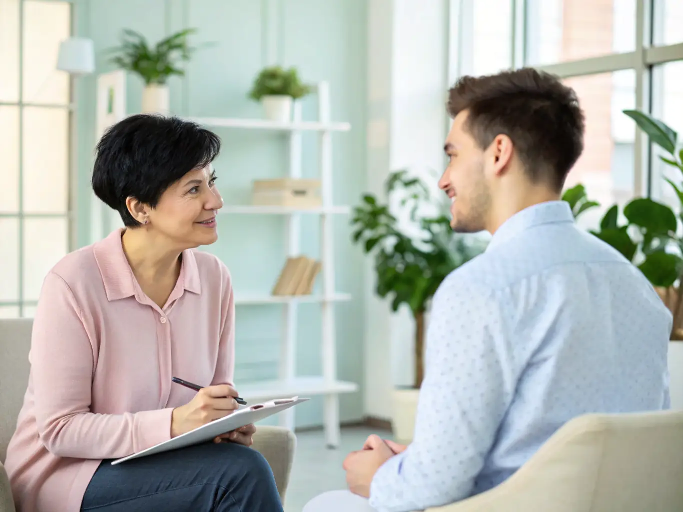 A professional recruiter is interviewing a candidate in a modern office setting. The recruiter is taking notes while the candidate is speaking, creating a focused and engaging atmosphere.